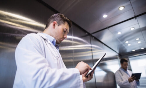 Doctor using digital tablet in corridor